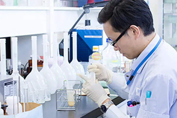 白衣を着た研究者が分析装置で実験している様子